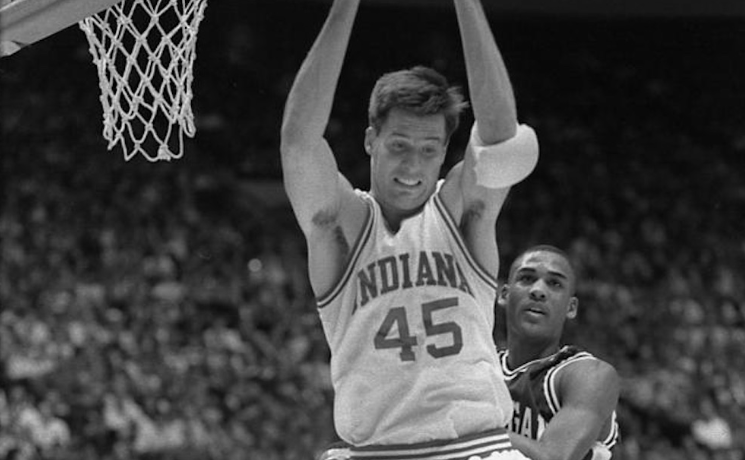 a black and white photo of brian sloan going up for a rebound in a white Indiana basketball jersey