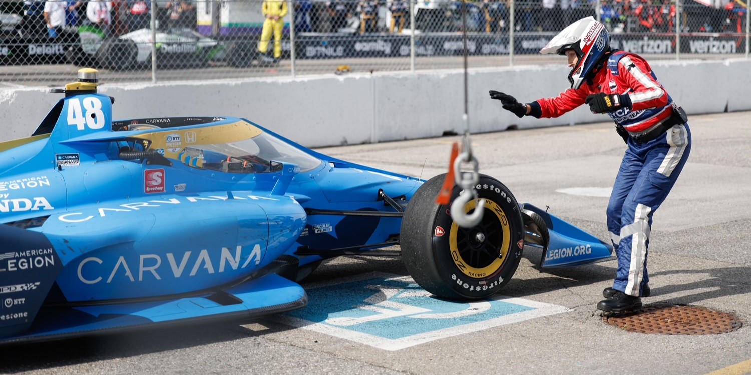 Dr. Melissa McCarthy engages with a driver in a blue racecar during a stop. 