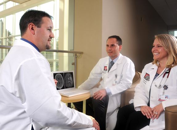 residents and faculty meet to discuss a case and review imaging on a computer screen